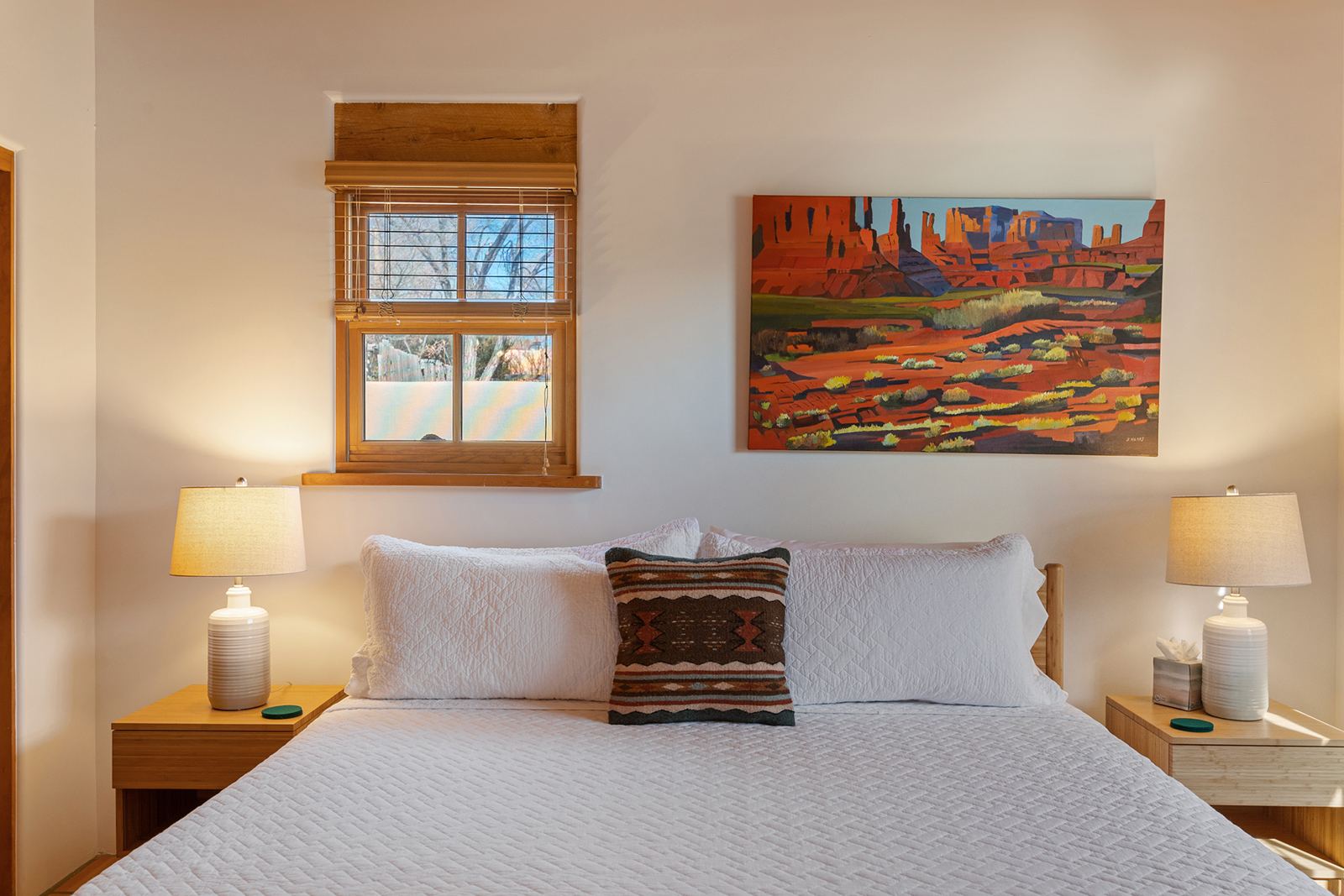 King bed with bedside lamps and a desert landscape painting