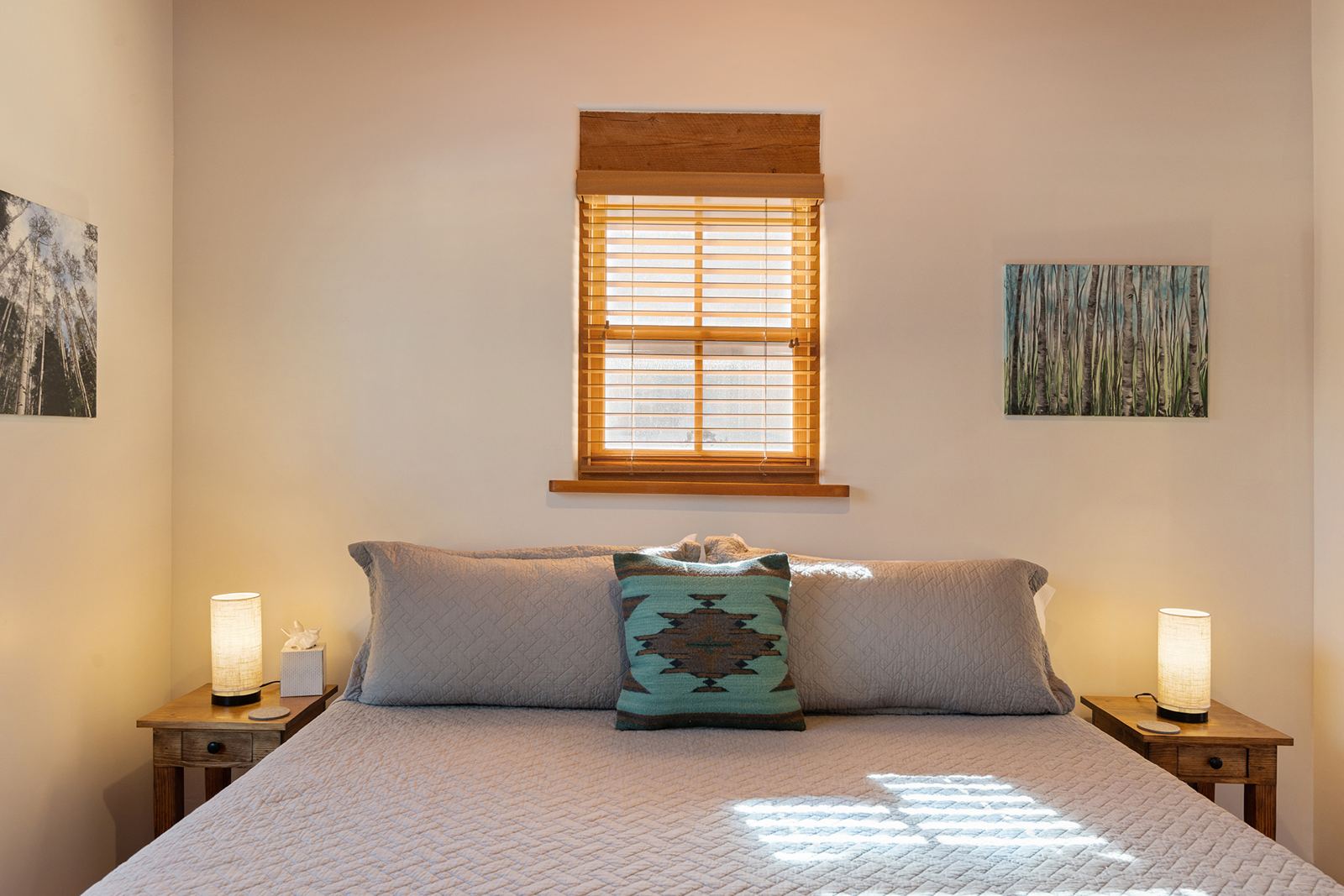 King bed with a turquoise pillow under a sunlit window