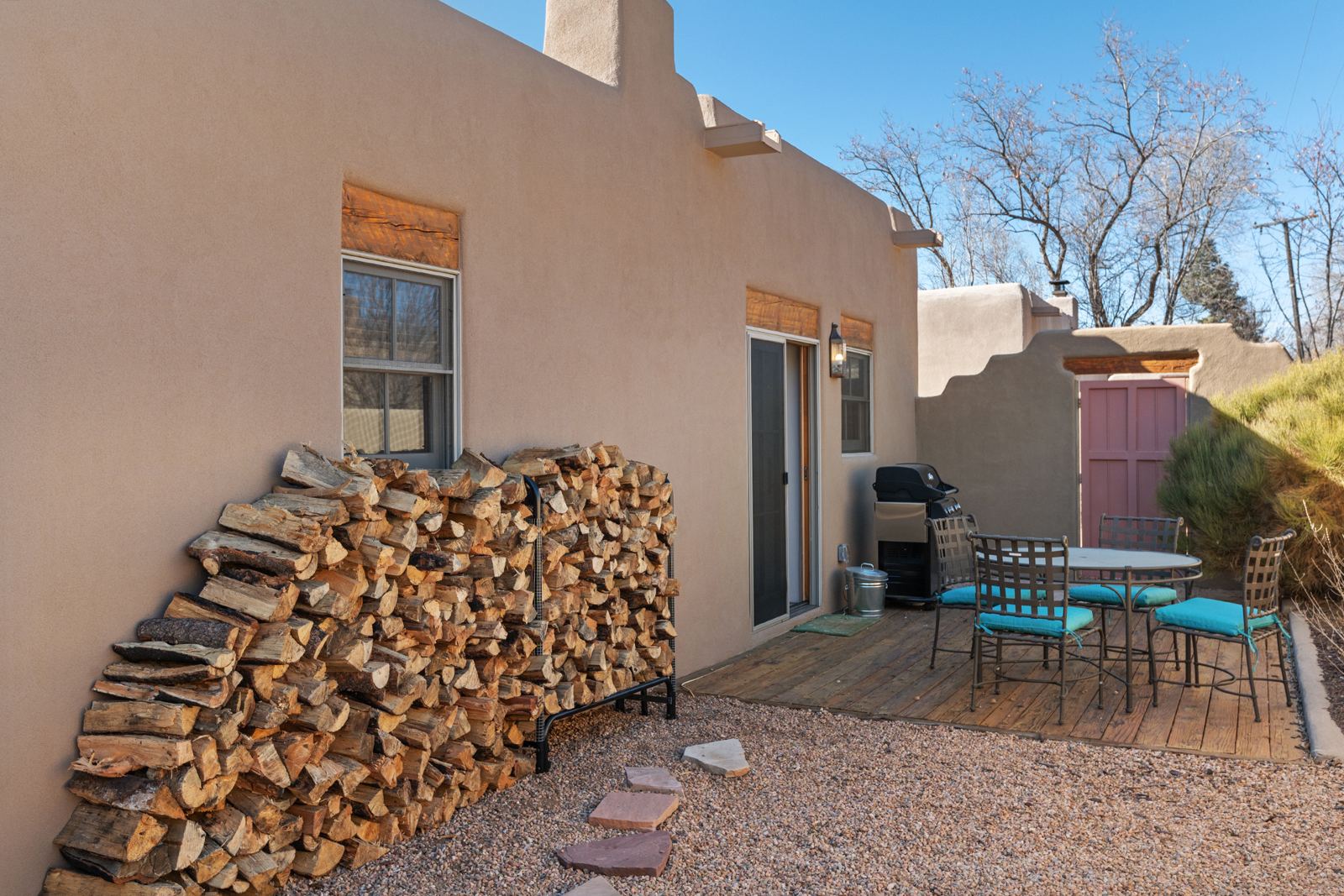 Private patio with gas grill, table and stacked firewood